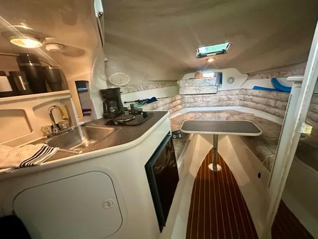 Slide: The Image of 1998 Rinker Fiesta Vee 266 cabin interior with kitchenette and seating area. - 14