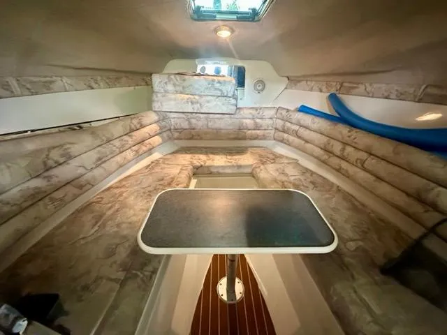 Slide: The Image of 1998 Rinker Fiesta Vee 266 cabin interior with table and seating, featuring cozy design. - 15