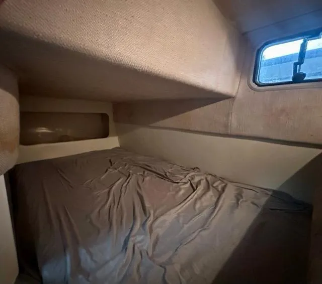 Slide: The Image of 1998 Rinker Fiesta Vee 266 cabin interior with bed and window. - 16