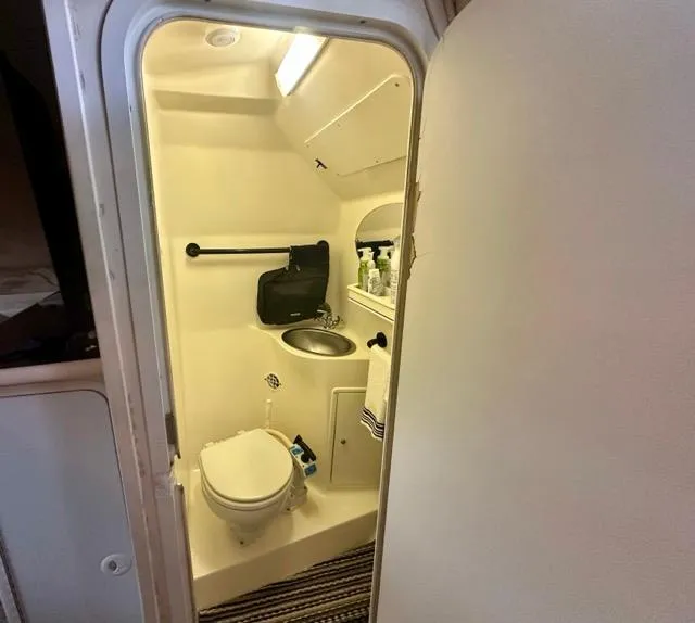 Slide: The Image of 1998 Rinker Fiesta Vee 266 boat bathroom with toilet, sink, and storage shelves. - 17