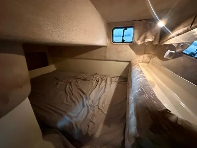 Slide: The Image of 1998 Rinker Fiesta Vee 266 cabin interior with bed, window, and light. - 19