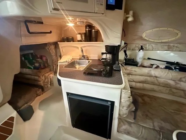 Slide: The Image of 1998 Rinker Fiesta Vee 266 cabin interior with kitchenette, sink, and seating area. - 20
