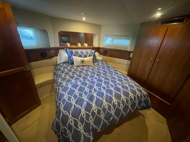 Slide: The Image of 1998 Carver 405 Aft Cabin bedroom with blue patterned bedding and wooden cabinetry. - 17
