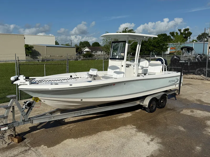 Slide: The Image of 2021 Robalo 246 Cayman boat on trailer, parked outdoors under a clear sky. - 1