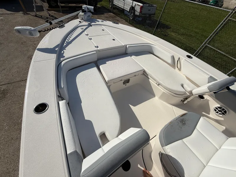 Slide: The Image of 2021 Robalo 246 Cayman boat interior with white seating and deck, docked outdoors. - 12