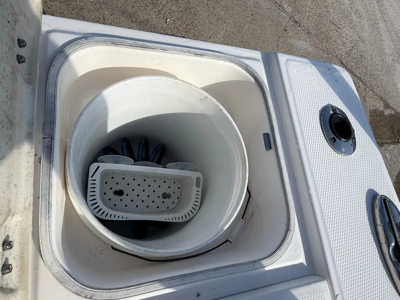 Slide: The Image of Livewell on 2021 Robalo 246 Cayman boat, featuring a white bucket and drain plug. - 25