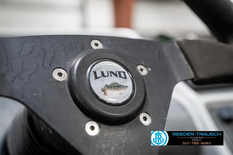 Slide: The Image of Steering wheel of 2001 Lund 1775 Pro V SE boat, featuring logo and fish emblem. - 37