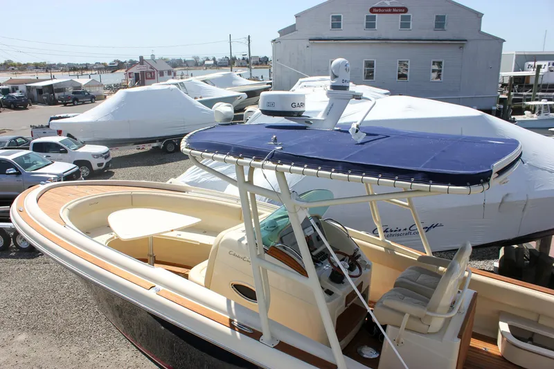 Slide: The Image of 2014 Chris-Craft Catalina 29 Sun Tender boat docked at a marina, featuring a blue canopy. - 34