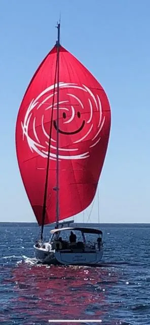 Slide: The Image of 2017 Beneteau Oceanis 41.1 sailboat with a red smiley face spinnaker on open water. - 1