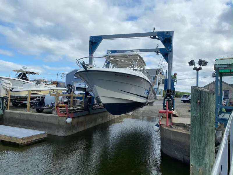 Slide: The Image of 2005 Hydra-Sports 3300 VX boat being lifted at a marina under a cloudy sky. - 2