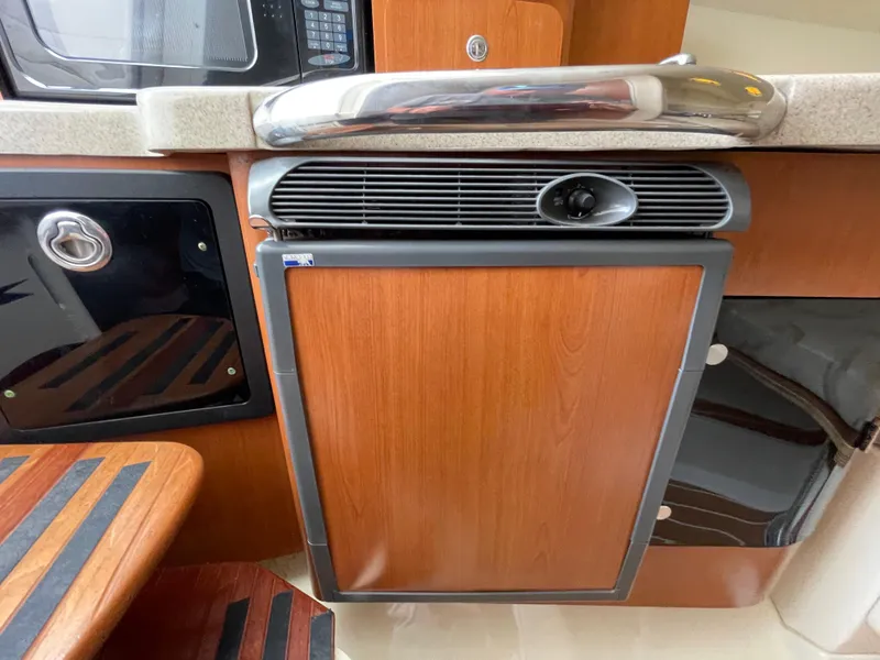 Slide: The Image of 2005 Hydra-Sports 3300 VX interior with wood paneling and compact kitchen appliances. - 29