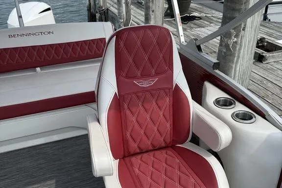 Slide: The Image of 2021 Bennington 24 RTSB boat with red and white diamond-stitched seating, docked by wooden pier. - 16