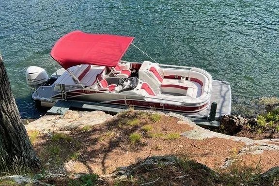 Slide: The Image of 2021 Bennington 24 RTSB pontoon boat with red canopy docked by a scenic lakeside. - 23
