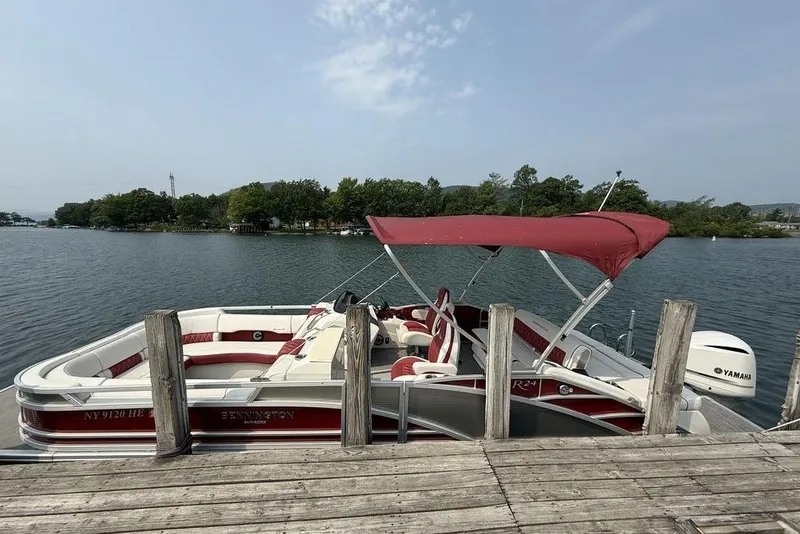 Slide: The Image of 2021 Bennington 24 RTSB pontoon boat docked with red canopy and Yamaha motor. - 6