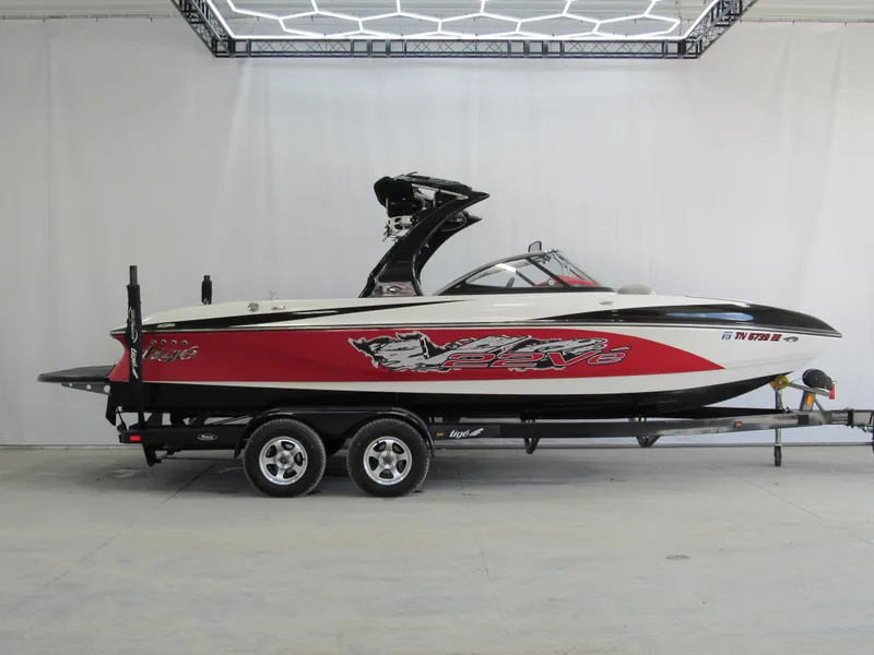 Slide: The Image of 2009 Tigé 22 EV boat with red and black design on a trailer in a showroom. - 0