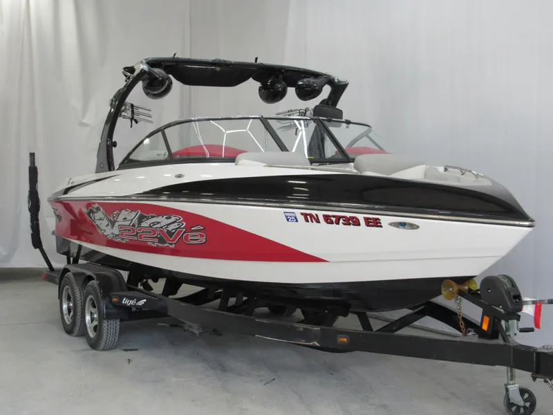 Slide: The Image of 2009 Tigé 22 EV boat on trailer, red and white design, indoor setting. - 1