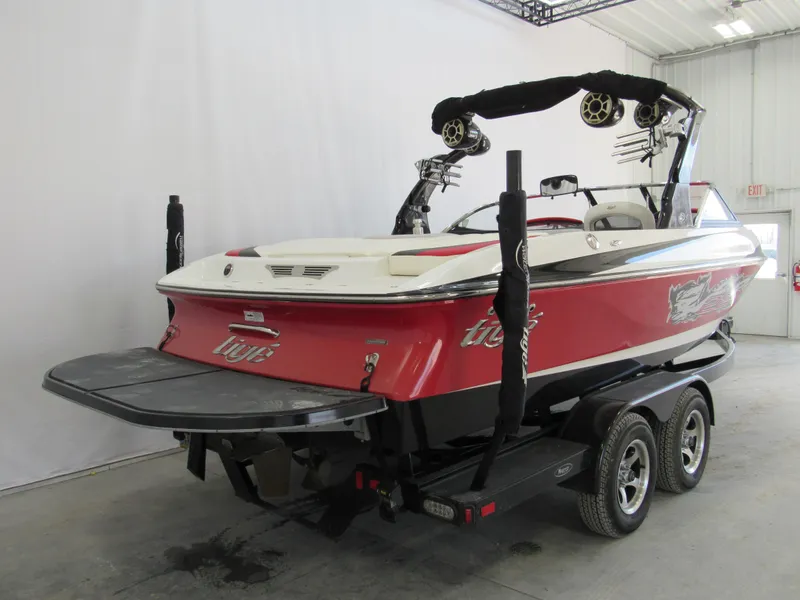 Slide: The Image of 2009 Tigé 22 EV boat on trailer, red and white, in indoor storage. - 2