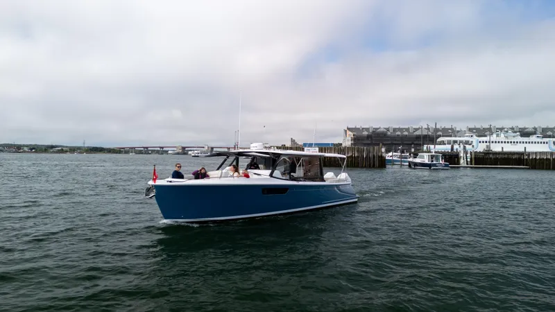 Slide: The Image of 2025 MJM 3 boat cruising near a harbor with passengers onboard. - 2