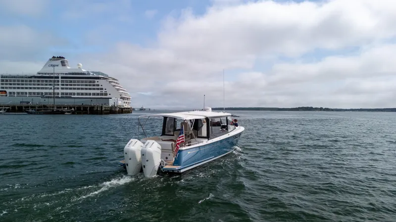 Slide: The Image of 2025 MJM 3 boat cruising near a large cruise ship on a cloudy day. - 3