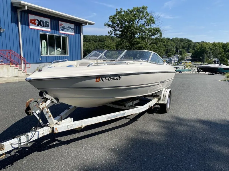 Slide: The Image of 2007 Stingray 195LR boat on trailer, parked outside a blue building on a sunny day. - 1