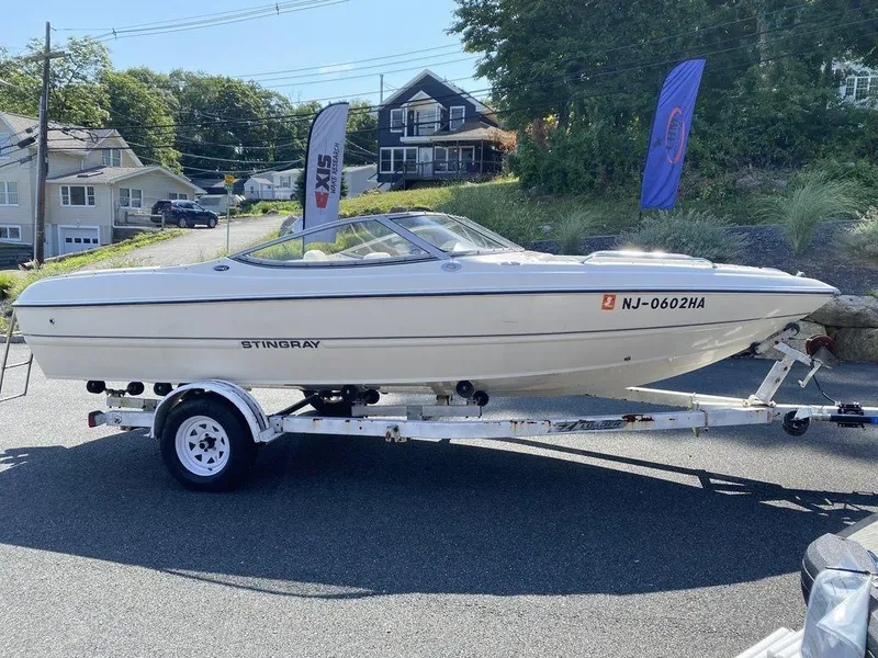 Slide: The Image of 2007 Stingray 195LR boat on trailer, parked outdoors with residential background. - 11