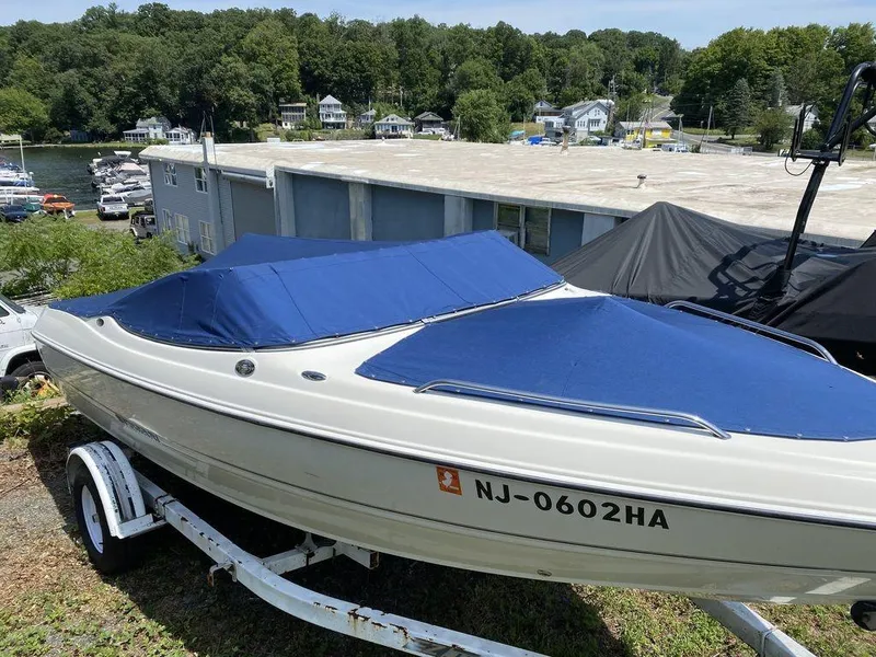 Slide: The Image of 2007 Stingray 195LR boat with blue cover on trailer, parked near waterfront buildings. - 9