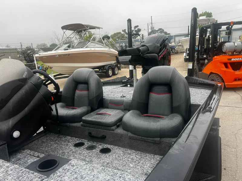 Slide: The Image of 2021 Bass Tracker 195 TX boat with dual seats and steering wheel, parked near other boats. - 6