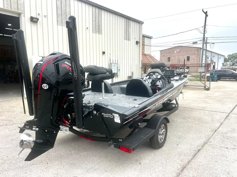 Slide: The Image of 2021 Bass Tracker 195 TX boat parked outside a warehouse, featuring a powerful outboard motor. - 9
