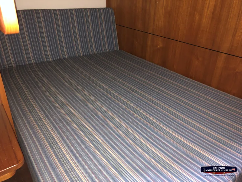 Slide: The Image of 2013 Tiara Yachts 3600 Coronet cabin with striped bedding and wooden interior. - 23