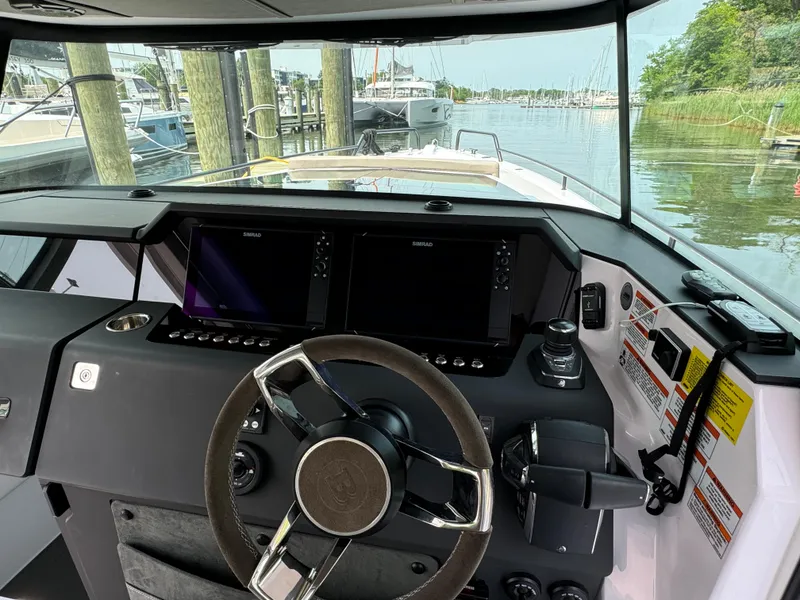 Slide: The Image of 2024 Axopar 37 Cross Cabin XC helm with dual screens and steering wheel. - 12
