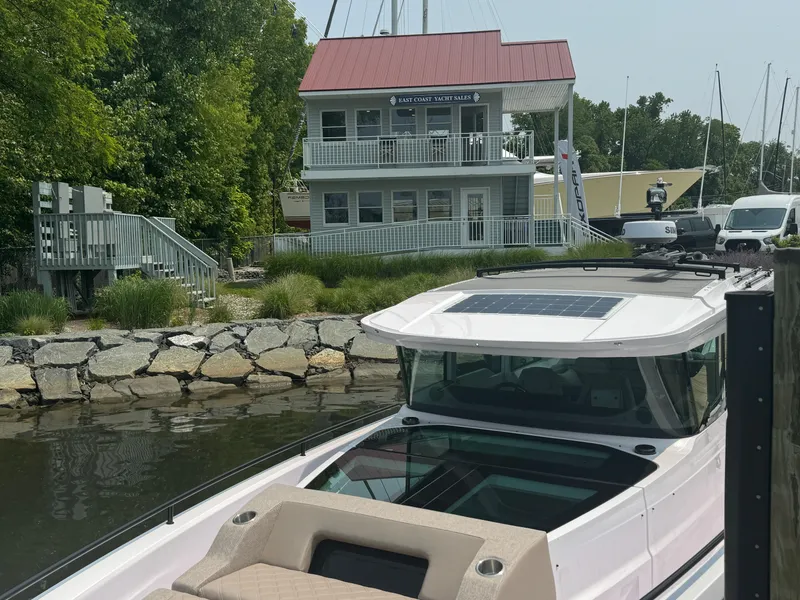 Slide: The Image of 2024 Axopar 37 Cross Cabin XC docked in a marina with sailboats. - 2