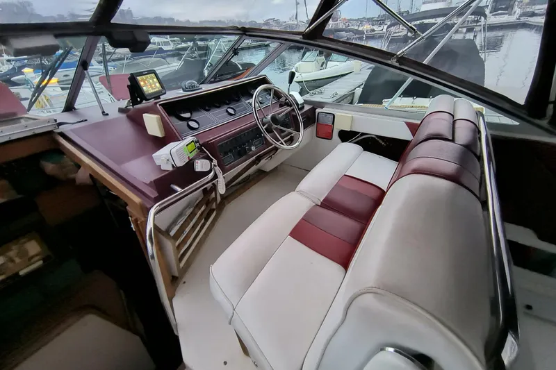 Slide: The Image of 1989 Sea Ray 268 Sun Dancer cockpit with maroon and white seating, steering wheel, and control panel. - 18
