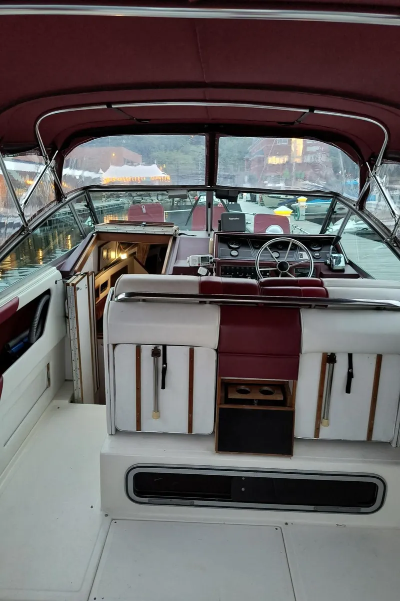 Slide: The Image of 1989 Sea Ray 268 Sun Dancer boat interior with maroon and white seating, steering wheel, and cabin entrance. - 21
