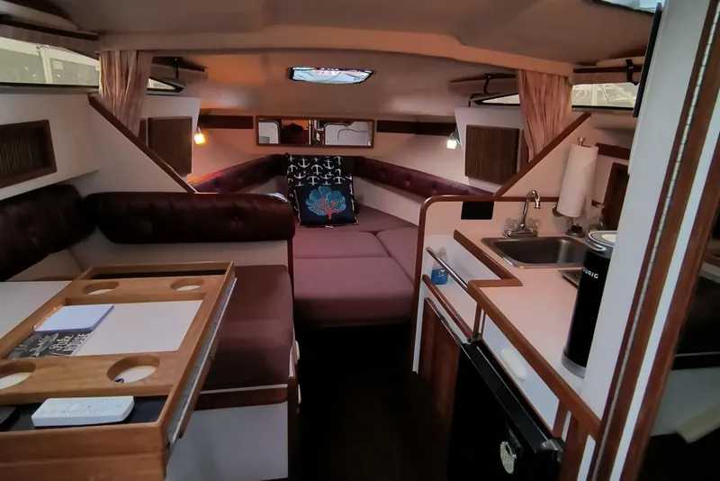 Slide: The Image of 1989 Sea Ray 268 Sun Dancer cabin interior with seating, kitchenette, and cozy sleeping area. - 5