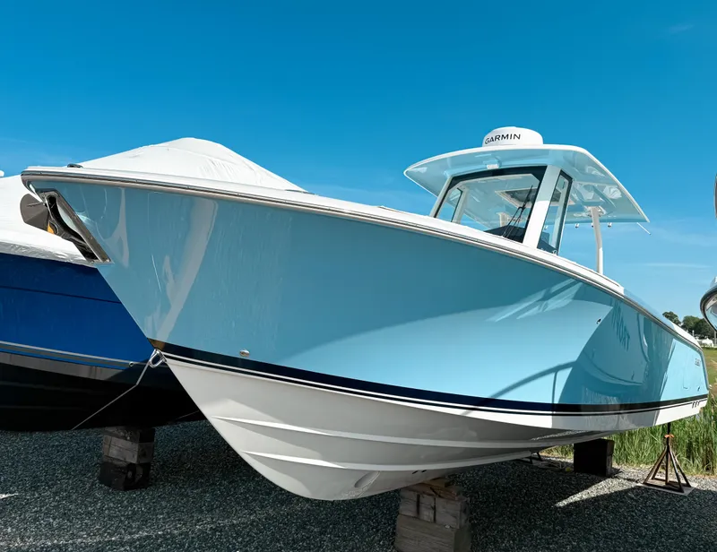 The Image of 2025 Pursuit S 288 Sport boat with sleek blue hull, docked outdoors. - 0