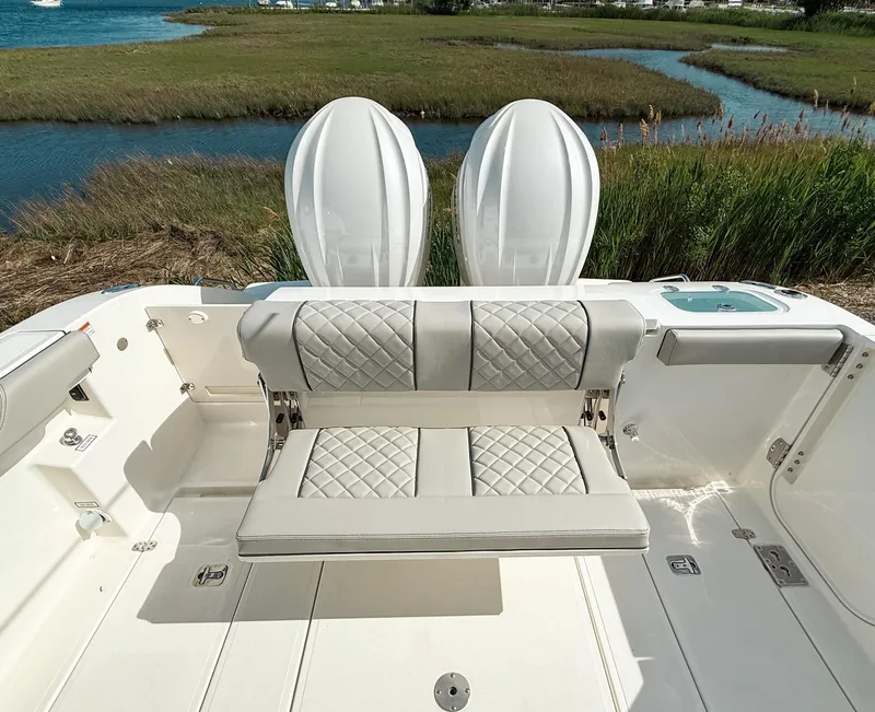 Slide: The Image of 2025 Pursuit S 288 Sport boat with luxurious seating and dual engines by a scenic waterway. - 9