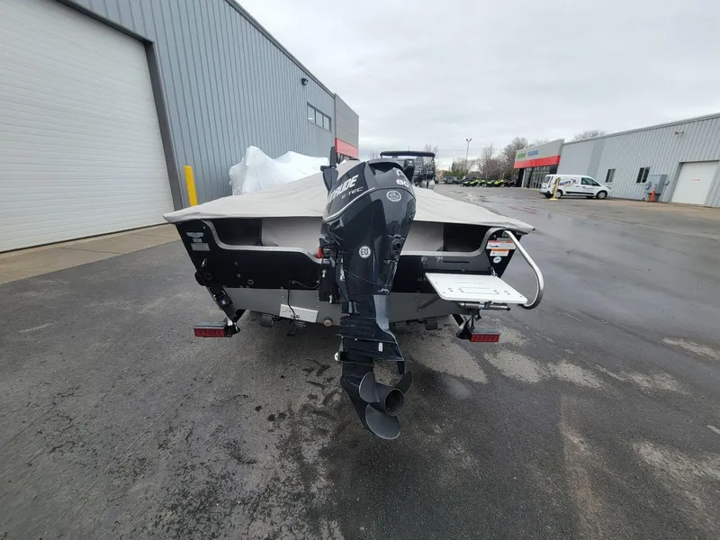 Slide: The Image of 2013 Lund 1650 Rebel XL Tiller boat with outboard motor, parked outside industrial building. - 10