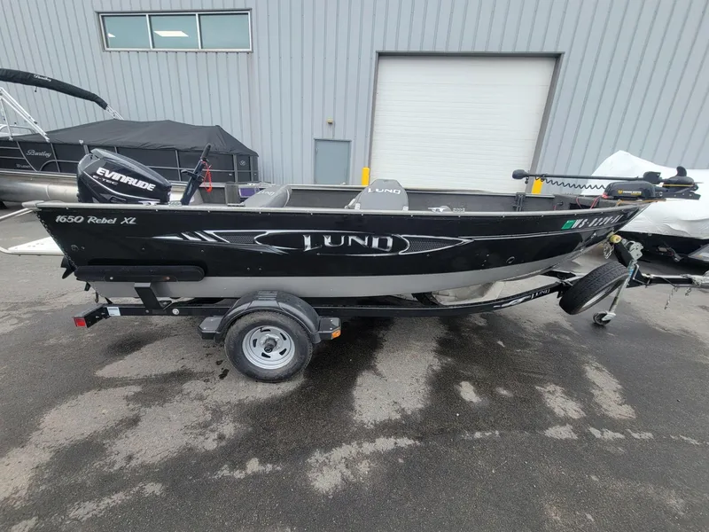 Slide: The Image of 2013 Lund 1650 Rebel XL Tiller boat on trailer, parked outdoors. - 13