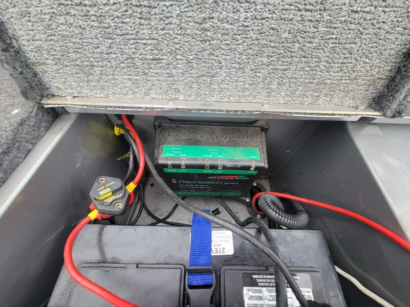 Slide: The Image of 2013 Lund 1650 Rebel XL Tiller boat battery compartment with wiring and charger. - 16