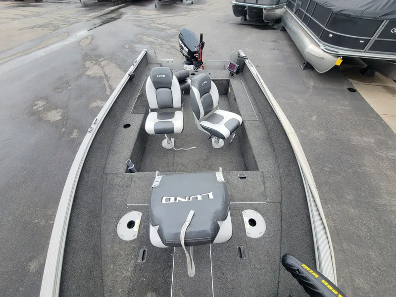 Slide: The Image of 2013 Lund 1650 Rebel XL Tiller boat with dual seats and motor, parked on pavement. - 19