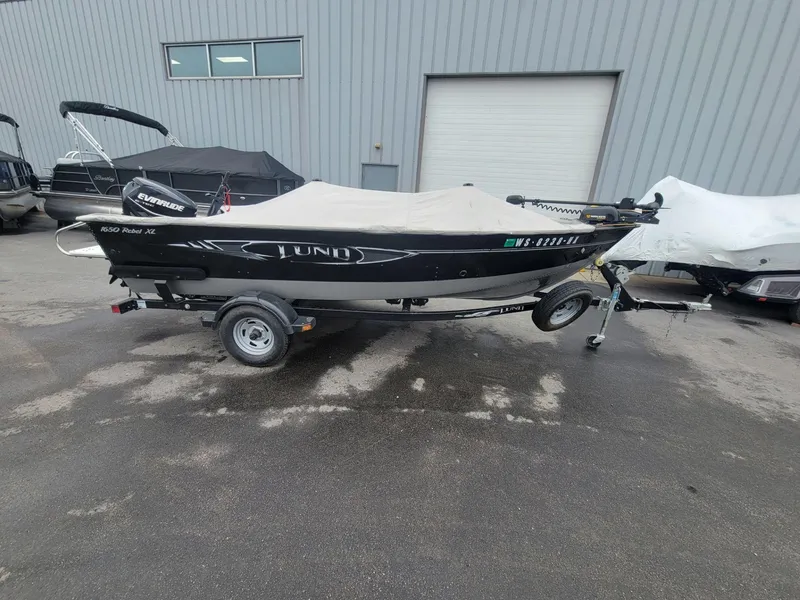 Slide: The Image of 2013 Lund 1650 Rebel XL Tiller boat on trailer, covered, parked outside. - 8