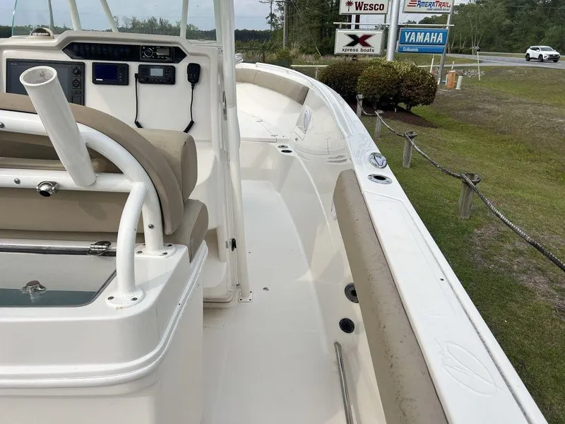 Slide: The Image of 2017 Sailfish 270 CC boat interior with beige seating and control panel, parked near dealership signs. - 19