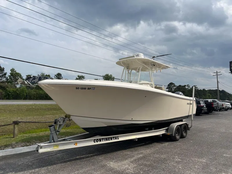 Slide: The Image of 2017 Sailfish 270 CC boat on trailer, parked outdoors under cloudy sky. - 2