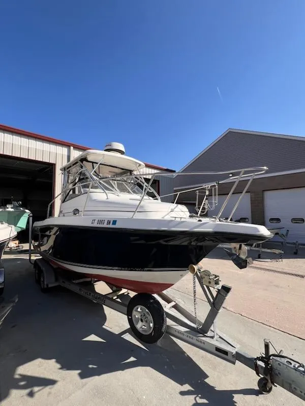 Slide: The Image of 2008 Century 2400 Walkaround boat on trailer, parked outside a garage under clear blue sky. - 1
