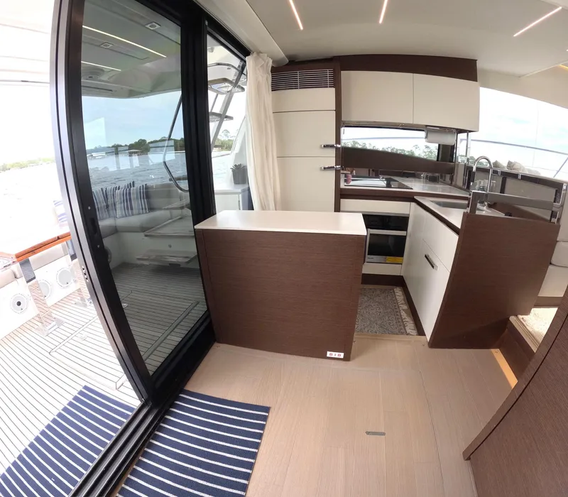 Slide: The Image of Modern kitchen interior on a 2019 Prestige 520 yacht, featuring sleek cabinetry and large windows. - 15