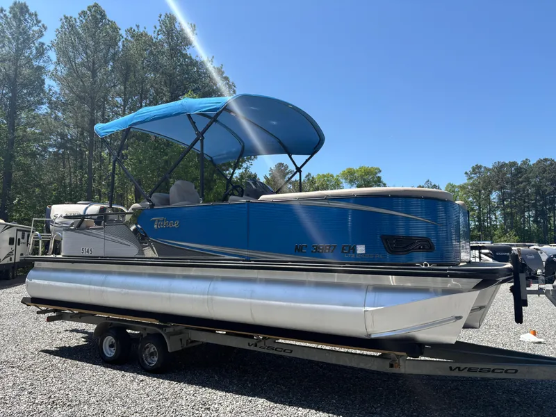 Slide: The Image of 2018 Avalon LSZ Quad Lounger pontoon boat with blue canopy on a trailer. - 4