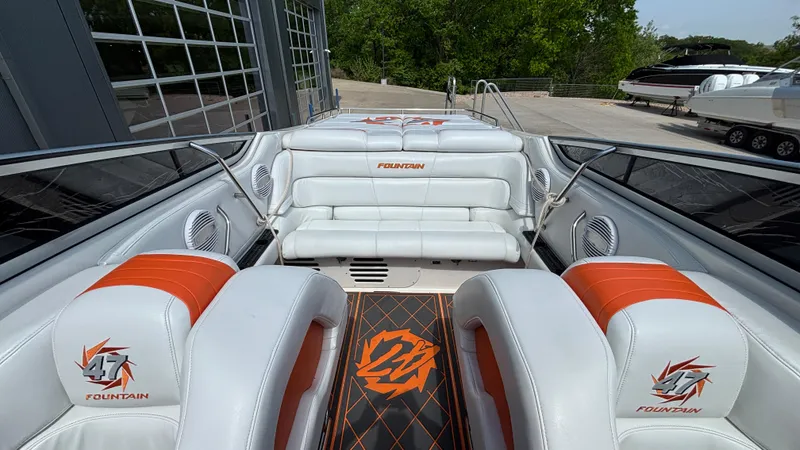 Slide: The Image of 2003 Fountain 47 Lightning boat interior with white and orange seating, docked near a marina. - 9