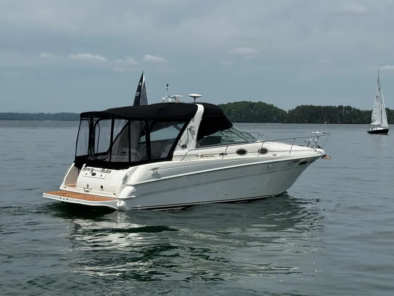 Slide: The Image of 2001 Sea Ray 290 Sundancer boat on calm water with distant sailboat. - 14