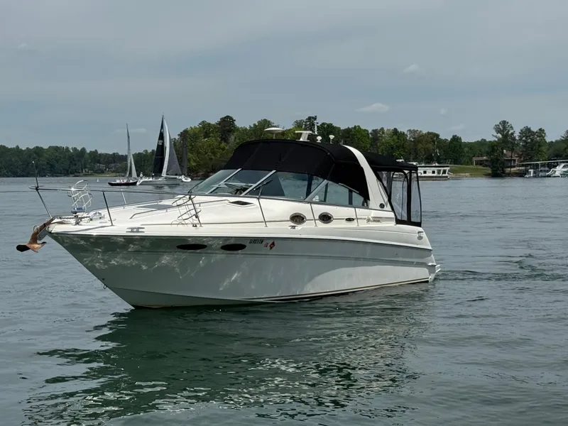Slide: The Image of 2001 Sea Ray 290 Sundancer boat on a calm lake with trees in the background. - 16