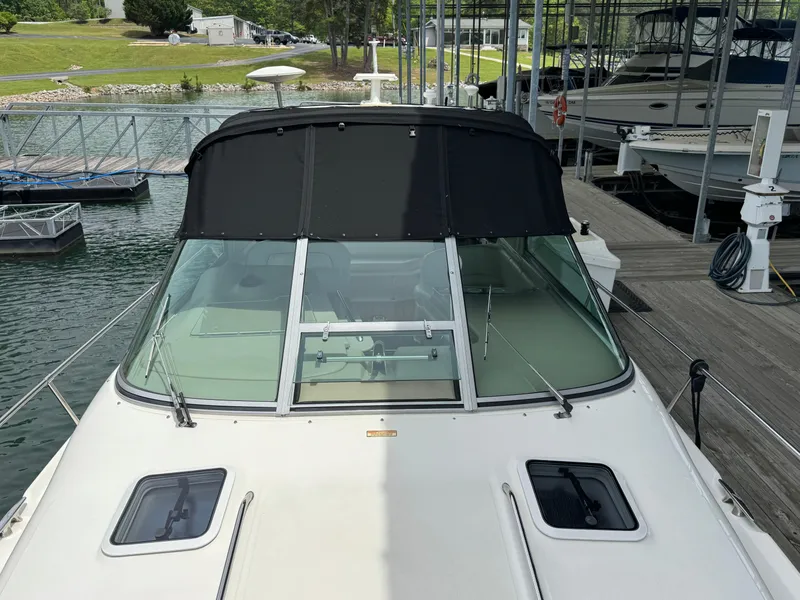 Slide: The Image of 2001 Sea Ray 290 Sundancer docked, featuring a sleek windshield and black canvas cover. - 18